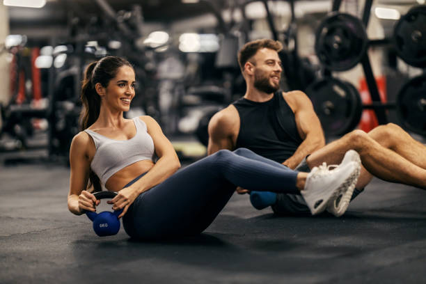 fit sporty couple in shape is doing kettlebell twist in a gym together.